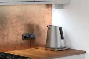 Kobieta buduje gniazda Simon 54 Premium pod szafką seria Simon 54 Premium wraz z natynkową puszką narożną